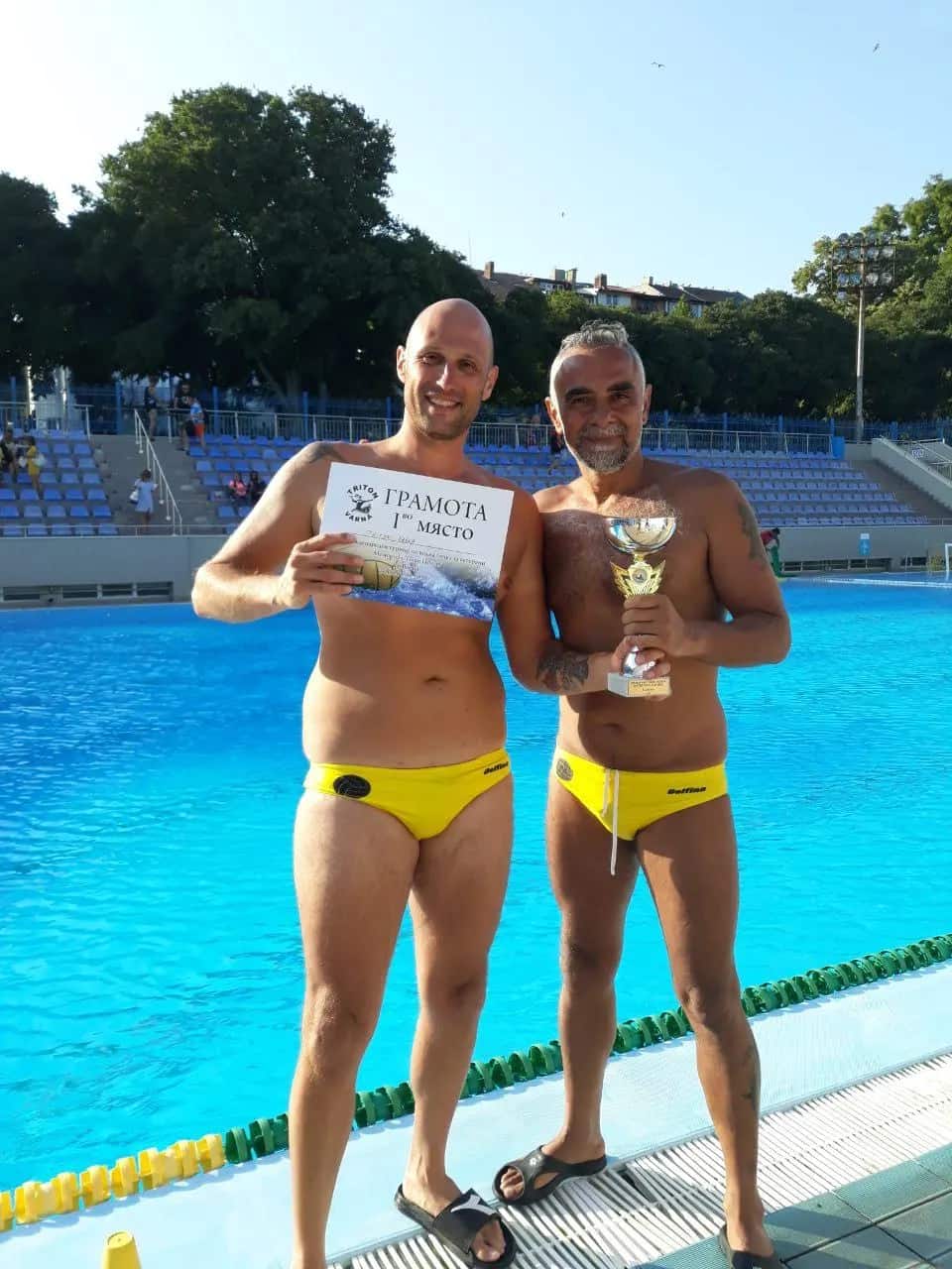 Two of the squad with the certificate and a cup by the pool